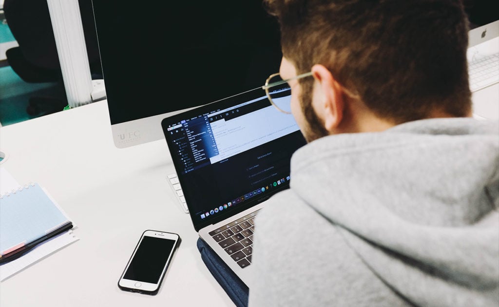 a sleek workspace with an open MacBook Pro showcasing a colorful, futuristic interface. This visual emphasizes innovation and technology, perfectly aligning with the theme of new features in iOS 18.2 Beta.